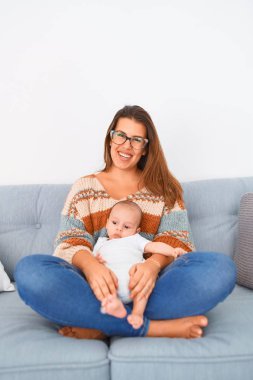 Genç, güzel bir kadın ve bebeği evdeki kanepede. Yeni doğan anne rahatlıyor ve dinleniyor.