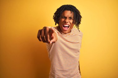 Çizgili t-shirt giyen dreadlocks giyen Afro adam izole sarı arka plan üzerinde rahatsız ve kameraya sinirli işaret, kızgın ve öfkeli size