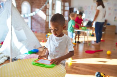 Anaokulunda bir sürü oyuncakla oynayan genç ve güzel öğretmen ve çocuklar.