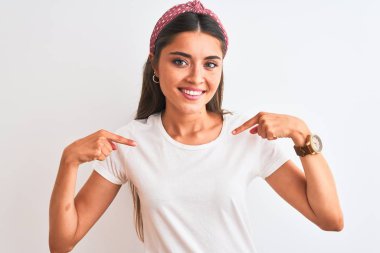 İzole edilmiş beyaz arka plan üzerinde gündelik tişört ve diyabet giyen genç ve güzel bir kadın. Yüzünde bir gülümsemeyle, gururlu ve mutlu bir şekilde kendini işaret ediyor..