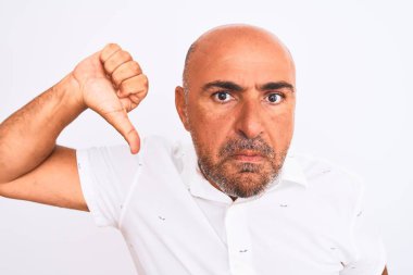 Orta yaşlı, şık gömlekli, soyutlanmış beyaz arka planda duran, kızgın yüzlü, negatif işaretli, baş parmaklı, reddedilme kavramlı, yakışıklı bir adam.
