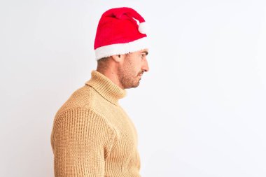 Yılbaşı ve balıkçı yaka kazak giyen genç yakışıklı bir adam izole bir arka plan arıyor, rahat profil pozu veriyor, kendine güvenen bir gülümsemesi var..