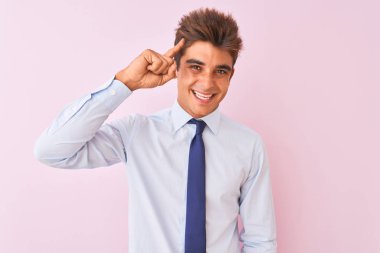 Tişört ve kravat takan yakışıklı genç bir işadamı pembe arka planda tek parmağıyla gülümseyerek, harika bir fikir ya da düşünceyle, iyi bir hafızayla.