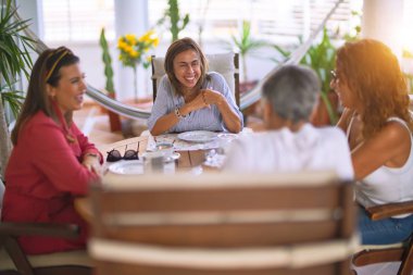 Genç ve güzel bir kız mutlu ve kendinden emin bir şekilde terasta oturmuş bir fincan kahve içiyor.