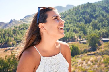 Genç, güzel bir kadın dağ manzarasında yaz tatilinin tadını çıkarıyor, gezgin kız mutlu gülümsüyor.