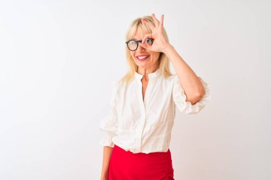 Orta yaşlı iş kadını gömlek ve gözlük takıyor. İzole edilmiş beyaz arka planda duruyor. El hareketleriyle gülümsüyor..