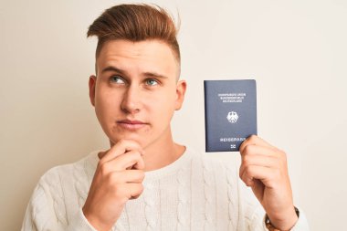 Alman pasaportu taşıyan yakışıklı genç bir adam izole edilmiş beyaz arka plan üzerinde ciddi bir yüz sorgulama ve kafa karıştırıcı bir fikir düşünüyor.