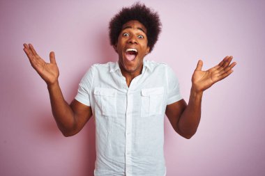 Afro saçlı, beyaz tişörtlü genç bir adam pembe arka planda dikilip çılgınlığı kutluyor ve kollarını kaldırıp heyecanla haykırarak başarıyı kutluyor. Kazanan konsept