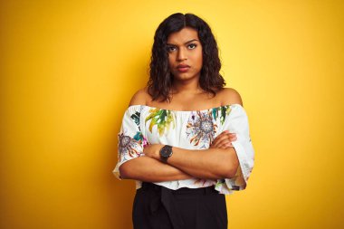 Transseksüel kadın, izole edilmiş sarı arka plan şüphecisi ve gergin, kolları çaprazlanmış yüz ifadesini tasvip etmeyen yaz tişörtü giyiyor. Negatif kişi.
