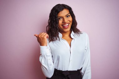 Güzel transseksüel transseksüel zarif iş kadını izole edilmiş pembe arka planda gülümseyen, gülümseyen ve baş parmağıyla yüzünü gösteren..