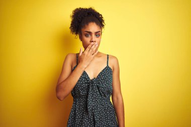 İzole edilmiş sarı arka plan üzerine günlük yeşil elbiseler giyen Afro-Amerikalı kadın ağzıyla esnemekten sıkılmış. Huzursuz ve uykulu..