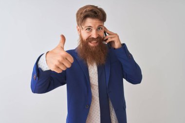 Genç kızıl saçlı İrlandalı işadamı, izole edilmiş beyaz arka plan üzerinden konuşuyor. Kocaman gülümsüyor. İşaret veriyor.