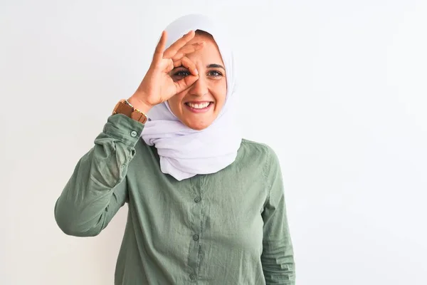 若いです美しいですアラブ女性身に着けています伝統的なイスラム教徒のヒジャーブ上の隔離された背景行いますOkジェスチャーとともに手笑顔 目を通して指で幸せな顔 — ストック写真