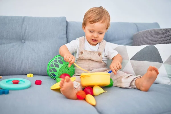 Sevimli Sarışın Çocuk Kanepede Oturup Evde Plastik Yemek Oyuncaklarıyla Oynuyor — Stok fotoğraf