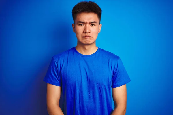 若いアジア系中国人男性のTシャツを着て隔離された青の背景の上に立って落ち込んで苦痛を心配し 怒っていると恐れて泣いている 悲しい表情 — ストック写真