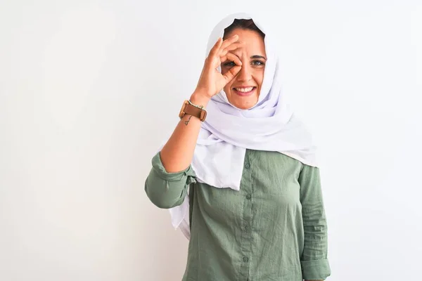 若いです美しいですアラブ女性身に着けています伝統的なイスラム教徒のヒジャーブ上の隔離された背景行いますOkジェスチャーとともに手笑顔 目を通して指で幸せな顔 — ストック写真