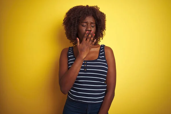 孤立した黄色の背景に縞模様のTシャツを着た若いアフリカのアフロ女性は 手で口をカバー疲れYawning退屈 眠れないのか — ストック写真
