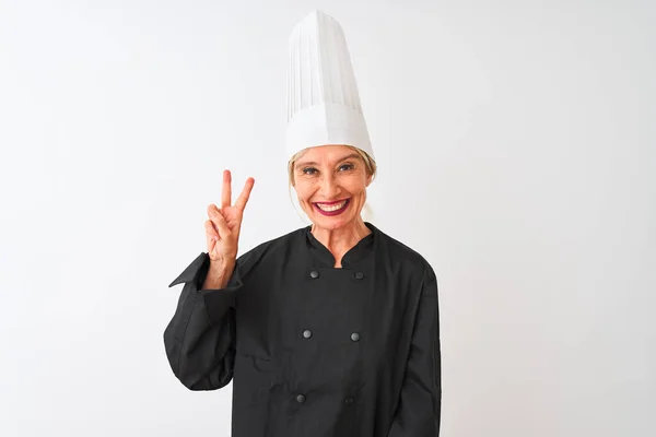 中年厨师女士身穿制服 头戴帽子 站在孤立的白色背景上 笑容满面 在镜头前眨眼示意胜利 第二点 — 图库照片