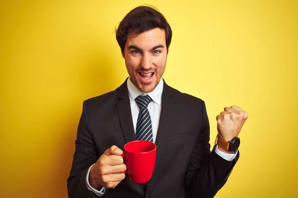 Junger Gutaussehender Geschäftsmann Trinkt Rote Tasse Kaffee Auf Isoliertem Gelben — Stockfoto