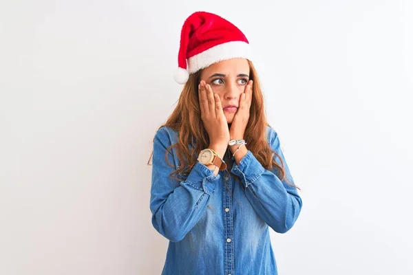 若いです美しい赤毛女性身に着けていますクリスマスの帽子上の隔離された背景疲れ手カバー顔 うつ病と悲しみ 動揺と問題のためにイライラ — ストック写真