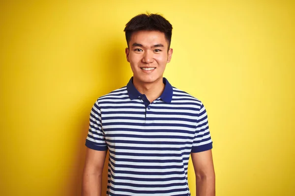 顔に幸せとクールな笑顔で孤立した黄色の背景の上に立ってストライプポロを身に着けている若いアジアの中国人男性 運のいい人 — ストック写真