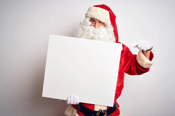 中年男子穿着圣诞老人的服装 拿着横幅挂在孤立的白色背景上 非常高兴地用手和手指指指点点 — 图库照片