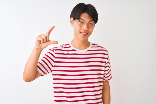 眼鏡とストライプのTシャツを身に着けている若い中国人男性は 指を見て カメラと小さなサイズの看板を行う手で孤立した白い背景笑顔と自信を持ってジェスチャーの上に立っています 概念の測定 — ストック写真