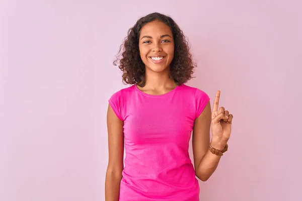 Jovem Brasileira Vestindo Camiseta Sobre Fundo Rosa Isolado Mostrando Apontando — Fotografia de Stock