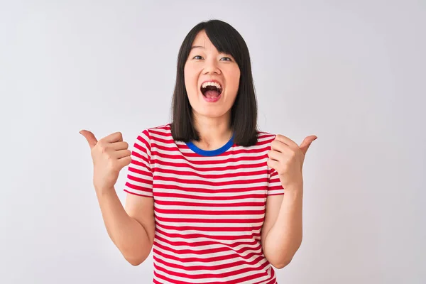 若い美しい中国の女性が赤い縞模様のTシャツを着て孤立した白い背景の成功のサインを手で積極的なジェスチャーを行う上で 親指を笑顔と幸せ 陽気な表情と勝者のジェスチャー — ストック写真