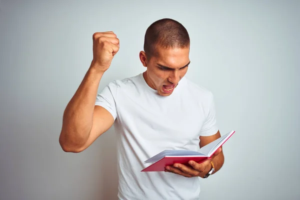 Νεαρός Όμορφος Άντρας Διαβάζει Κόκκινο Βιβλίο Πάνω Από Λευκό Απομονωμένο — Φωτογραφία Αρχείου