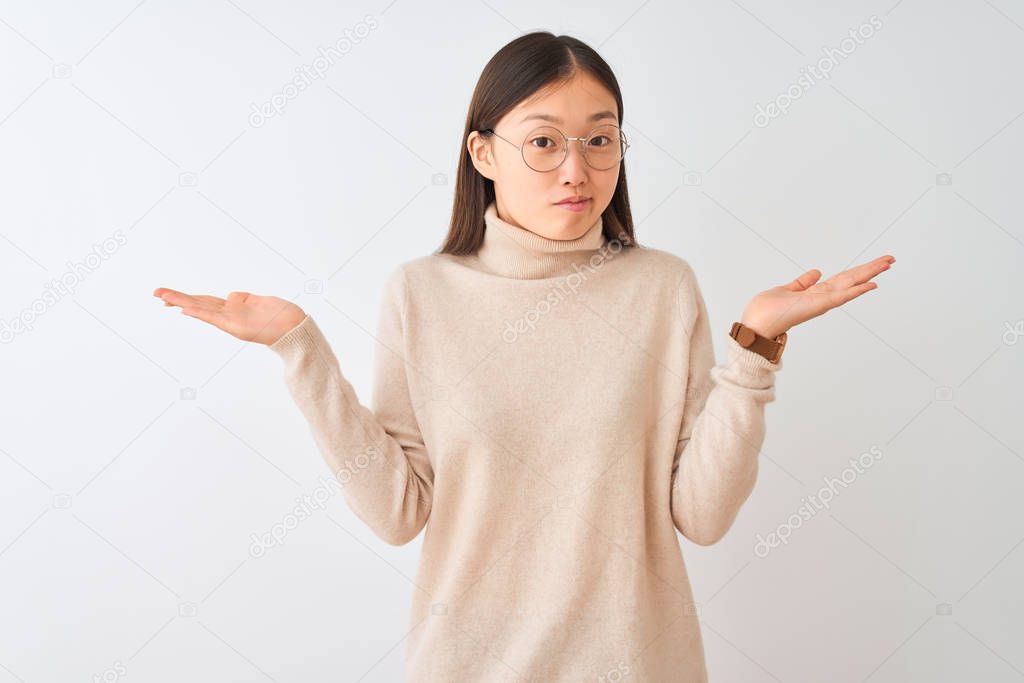 Young chinese woman wearing turtleneck sweater and glasses over isolated white background clueless and confused expression with arms and hands raised. Doubt concept.