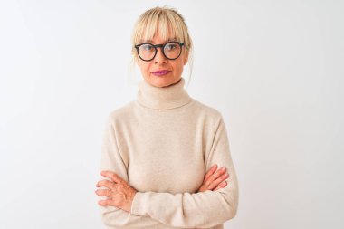 Balıkçı yaka kazak ve gözlük takan orta yaşlı bir kadın izole edilmiş beyaz arka plan üzerine rahatlamış ve yüzünde ciddi bir ifade vardı. Basit ve doğal bir şekilde kameraya bakıyorsun..