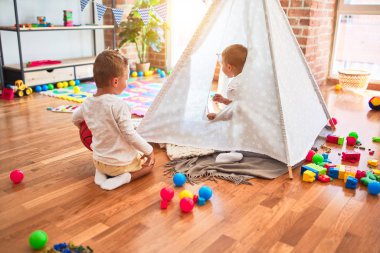 Güzel sarışın ikizler anaokulunda bir sürü oyuncakla oynuyorlar.