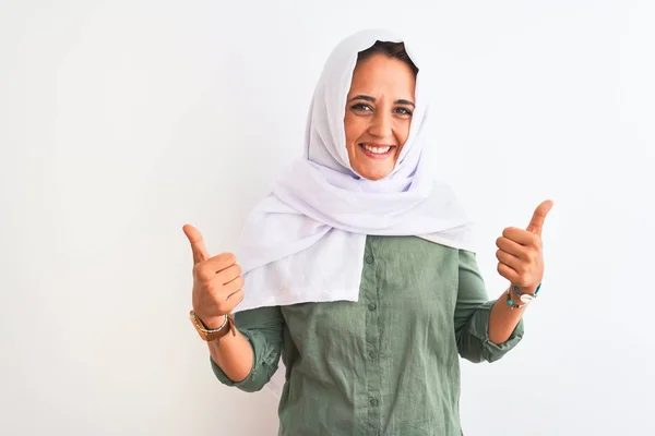 孤立した背景成功サインの上に伝統的なイスラム教徒のヒジャーブを身に着けている若い美しいアラブの女性は 手で積極的なジェスチャーを行います 親指を笑顔と幸せ 陽気な表情と勝者のジェスチャー — ストック写真