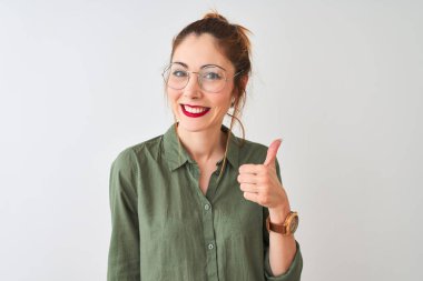 Yeşil tişörtlü ve gözlüklü kızıl saçlı bir kadın izole edilmiş beyaz arka planda durup mutlu bir el hareketi yapıyor. Kameraya bakıp başarıyı gösteren ifade onaylanıyor.