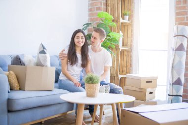 Genç güzel çift karton kutular etrafında yeni evde kahve içme kanepede oturan