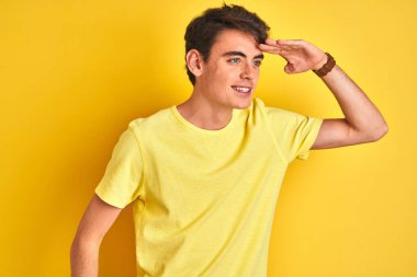 İzole edilmiş arka plan üzerinde sarı t-shirt giyen genç çocuk çok mutlu ve tebessüm ediyor. Konsept aranıyor.
