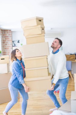 Genç güzel çift yeni evde karton kutu yığını tutan