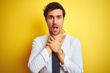 Zarif gömlek ve kravat giyen genç yakışıklı iş adamı izole edilmiş sarı arka planda bağırıyor ve boğuluyor çünkü acı verici bir boğulma var. Sağlık problemi. Boğulma ve intihar konsepti.