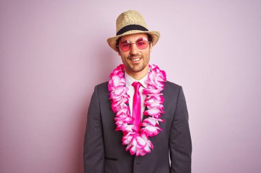 Takım elbiseli genç iş adamı gözlüklü Hawai leyleği, pembe arka planda mutlu bir yüz, kendine güvenen bir gülümsemeyle dişlerini gösteriyor.