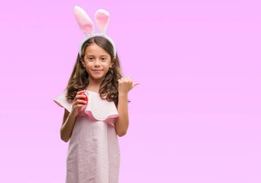 Paskalya tavşanı işaret ve başparmak kadar mutlu yüz gülümseyen tarafı ile gösterilen kulakları giyen esmer Latin kız