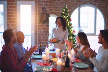 Mutlu ve kendinden emin gülümseyen güzel bir aile. Kavrulmuş hindiyi göstermek ve evde Noel 'i kutlamak.