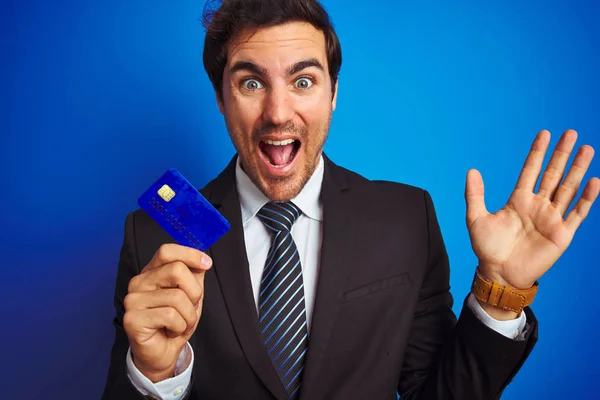Молодой Красивый Бизнесмен Держащий Кредитную Карту Стоя Изолированном Синем Фоне — стоковое фото