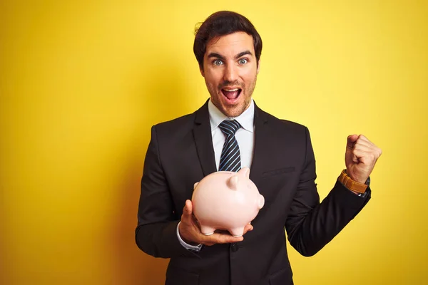 Joven Hombre Negocios Guapo Sosteniendo Alcancía Sobre Fondo Amarillo Aislado — Foto de Stock