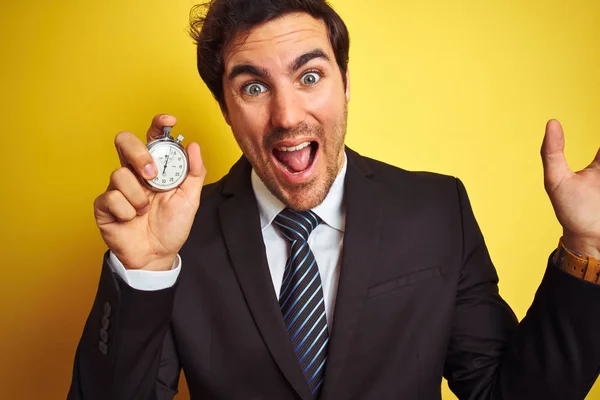 Joven Hombre Negocios Guapo Sosteniendo Cronómetro Pie Sobre Fondo Amarillo — Foto de Stock