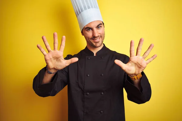 年轻的厨师 身穿制服 头戴帽子 站在孤立的黄色背景上 带着自信和快乐的笑容 指指点着十号 — 图库照片