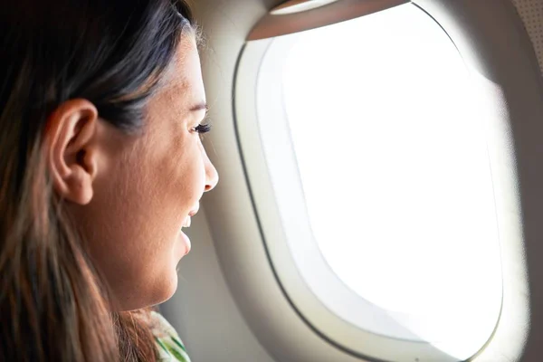 Young traveller woman sitting inside plane at the airport with sky view from the window