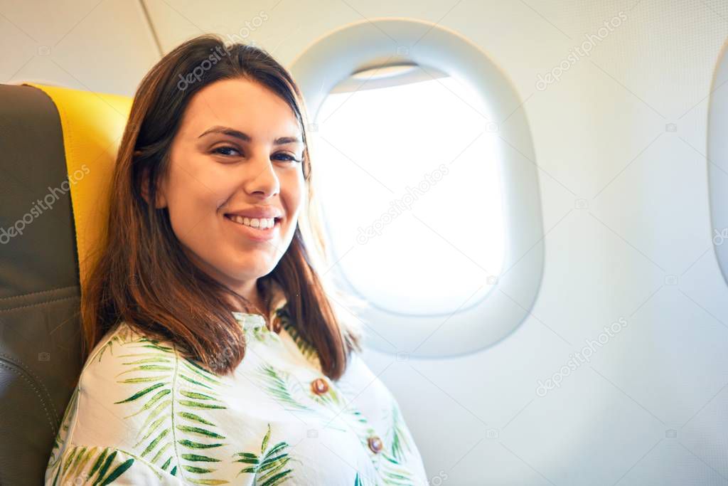 Young traveller woman sitting inside plane at the airport with sky view from the window