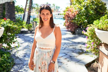 Genç, güzel bir kadın gülümsüyor. Mutlu, güneşli bir yaz gününün tadını çıkarıyor.