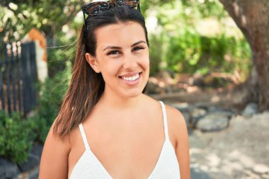 Güneşli bir yaz gününde yeşil parkta mutlu ve neşeli gülümseyen güzel bir kadın.